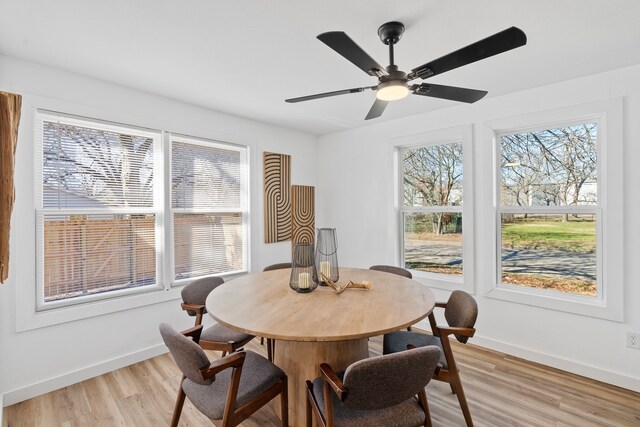 dining space featuring a ceiling fan, light wood-type flooring, and baseboards