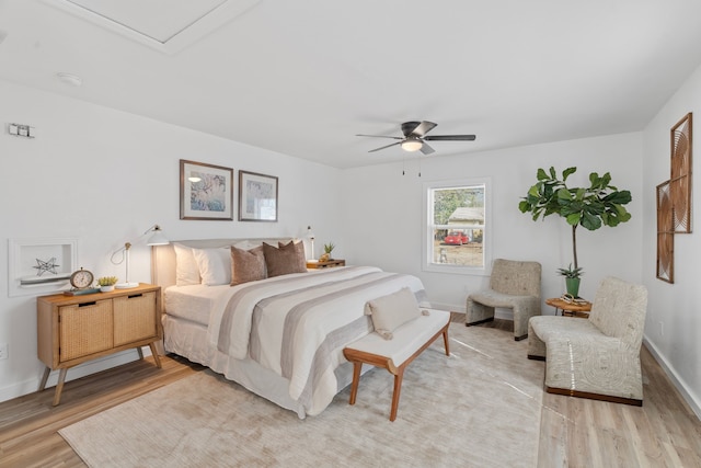 bedroom with light wood finished floors, a ceiling fan, and baseboards