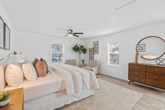 bedroom with a ceiling fan, baseboards, and light wood finished floors