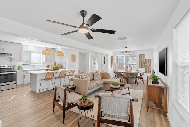 living room featuring a ceiling fan, visible vents, and light wood-style flooring