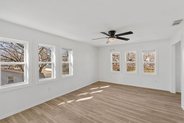 empty room with light wood-style floors, visible vents, baseboards, and a ceiling fan