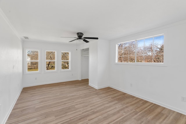 empty room with light wood-style floors, baseboards, visible vents, and a wealth of natural light