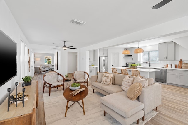 living area with visible vents, ceiling fan, and light wood finished floors