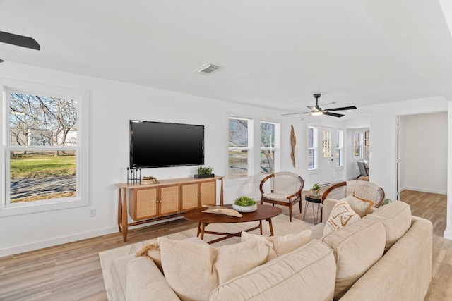 living area with light wood-style flooring, a ceiling fan, visible vents, and a healthy amount of sunlight