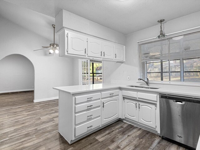 kitchen with a peninsula, a sink, white cabinets, light countertops, and dishwasher