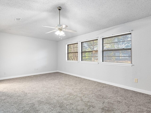 unfurnished room featuring a textured ceiling, carpet flooring, visible vents, a ceiling fan, and vaulted ceiling