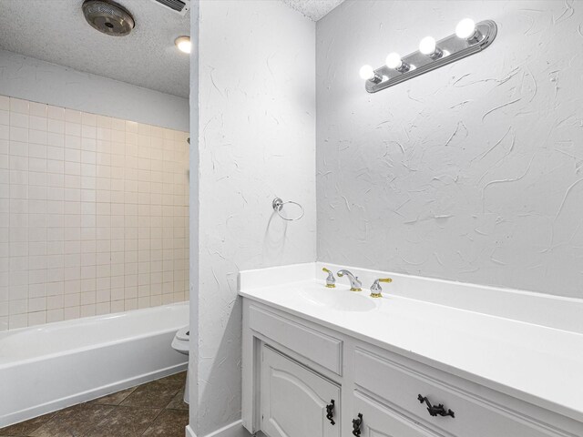 bathroom featuring a textured ceiling, a textured wall, tile patterned flooring, toilet, and vanity