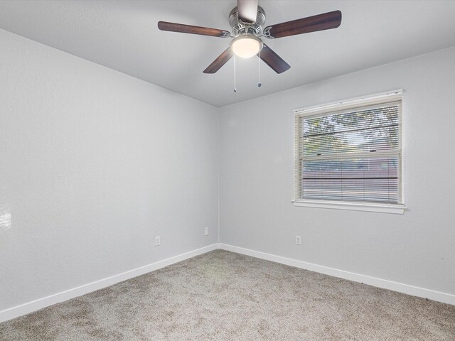 carpeted spare room featuring a ceiling fan and baseboards