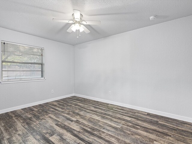 unfurnished room featuring a textured ceiling, dark wood-type flooring, a ceiling fan, and baseboards