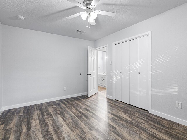 unfurnished bedroom featuring baseboards, a textured ceiling, visible vents, and dark wood-style flooring