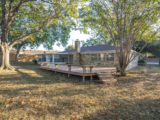 rear view of house with a chimney, a fenced backyard, a lawn, and a deck