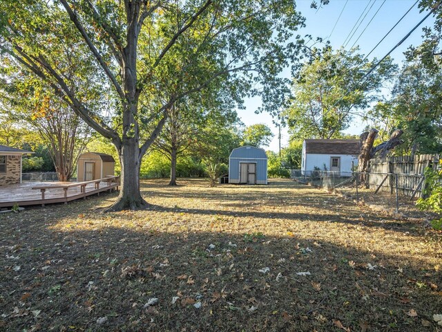 view of yard with an outdoor structure, a deck, and a shed