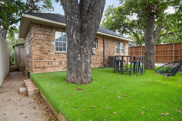 view of yard featuring central AC and fence