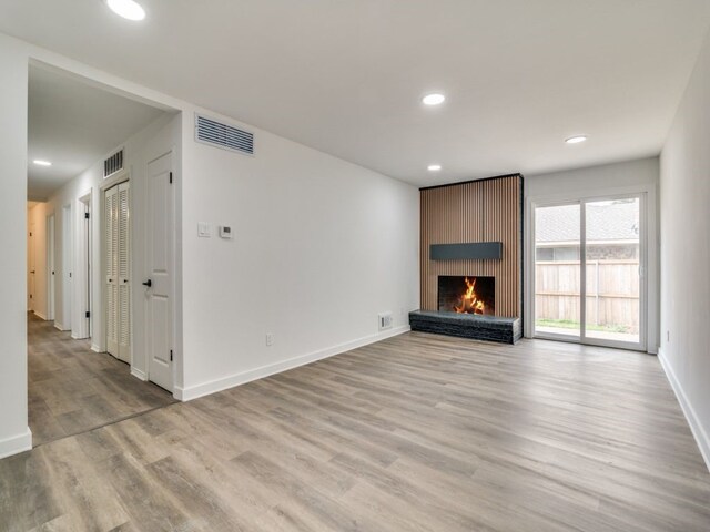 unfurnished living room with light wood finished floors, baseboards, visible vents, a fireplace, and recessed lighting