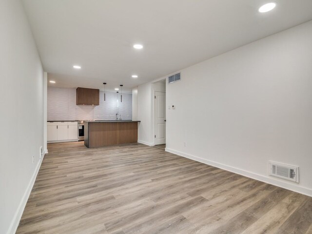 unfurnished living room with light wood-style floors, recessed lighting, visible vents, and baseboards