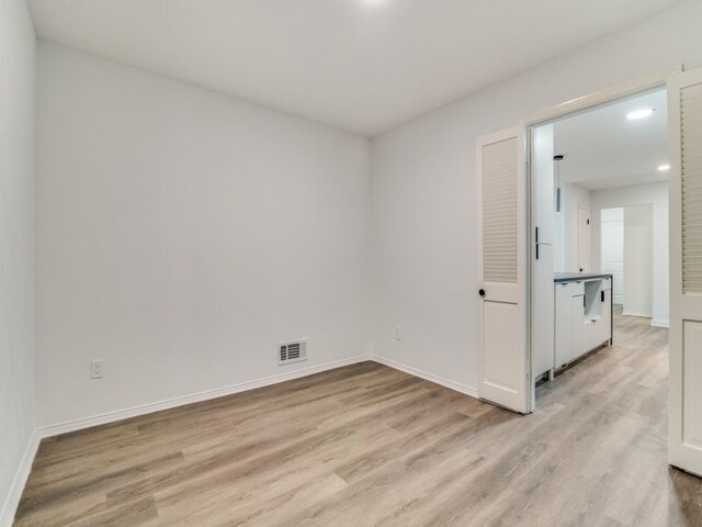 empty room with light wood-style floors, baseboards, and visible vents