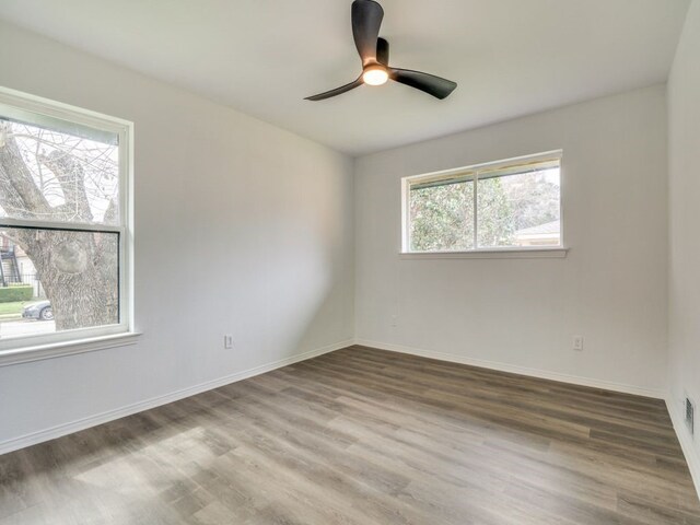 spare room featuring wood finished floors, a ceiling fan, and baseboards