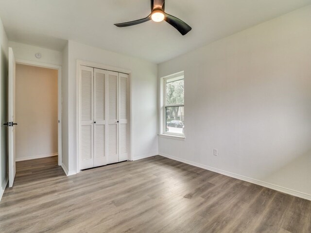 unfurnished bedroom with baseboards, a closet, a ceiling fan, and light wood-style floors