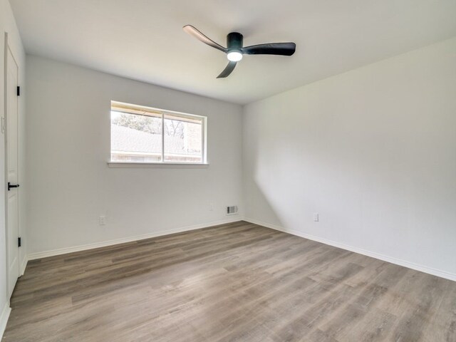 unfurnished room with ceiling fan, light wood-type flooring, visible vents, and baseboards