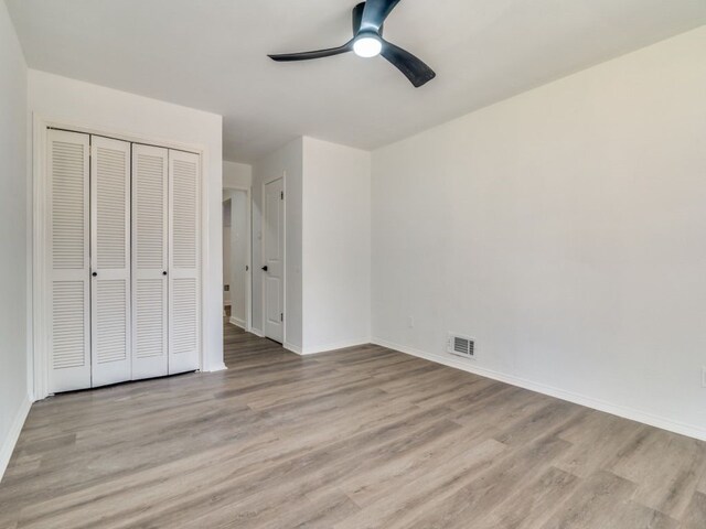 unfurnished bedroom featuring baseboards, a closet, visible vents, and light wood-style floors