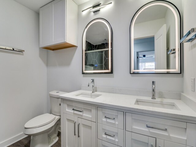 full bath with double vanity, a sink, toilet, and baseboards