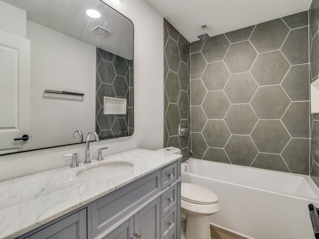 bathroom with toilet, vanity, and a combined bath / shower with rainfall shower