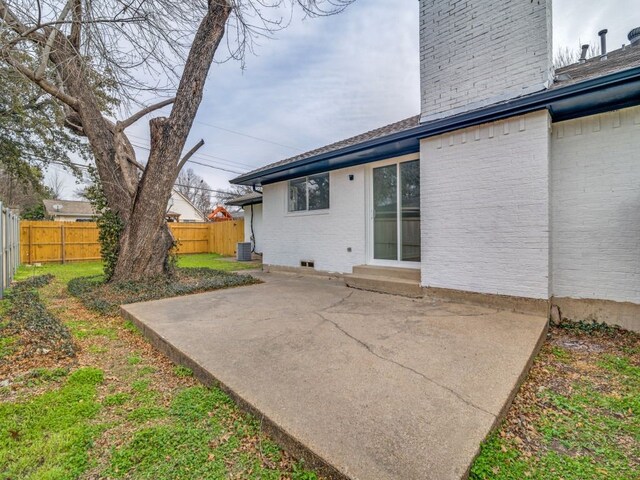 back of property with a patio area, brick siding, central AC, and a fenced backyard