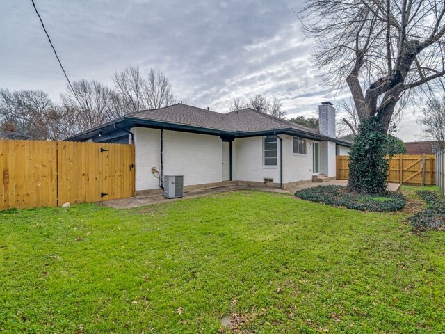 view of side of property featuring a yard, brick siding, a fenced backyard, and a gate