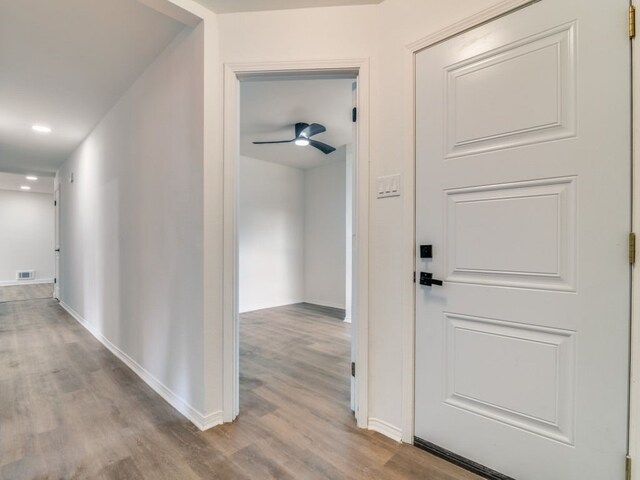 hallway with light wood-style flooring, visible vents, and baseboards