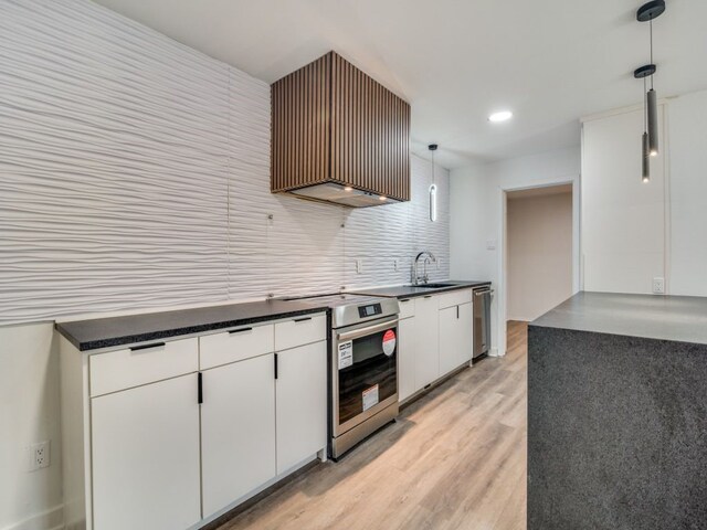 kitchen featuring a sink, stainless steel range with electric cooktop, white cabinets, dark countertops, and decorative light fixtures