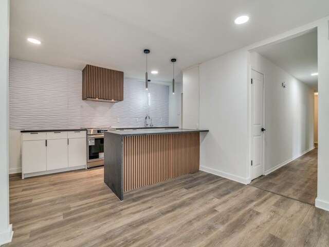 kitchen with white cabinetry, light wood-type flooring, range, dark countertops, and pendant lighting