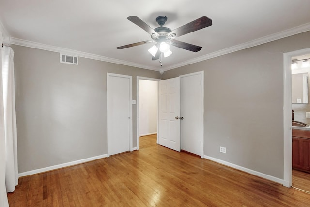 unfurnished bedroom featuring crown molding, visible vents, connected bathroom, light wood-type flooring, and baseboards