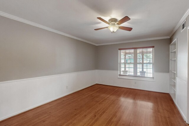 spare room featuring ornamental molding, wood finished floors, visible vents, and a ceiling fan