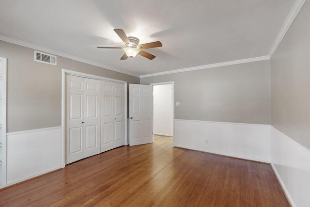 unfurnished bedroom featuring visible vents, crown molding, and wood finished floors