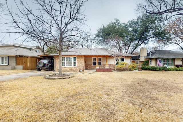 single story home featuring driveway, stone siding, a chimney, an attached carport, and a front yard