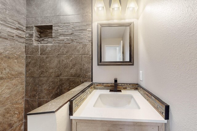 bathroom with a textured wall and vanity