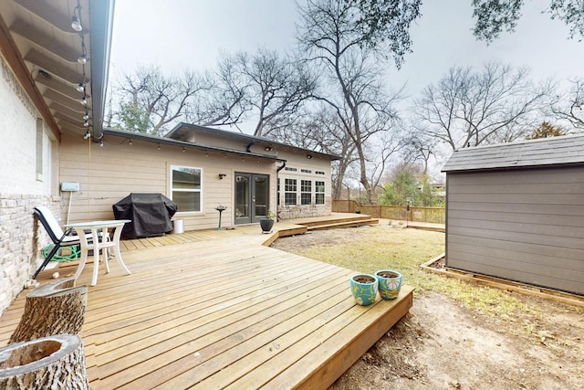 deck with a storage unit, fence, an outbuilding, and area for grilling