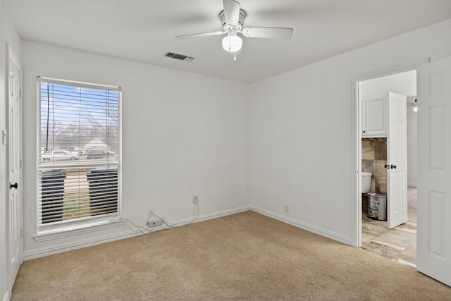 empty room with light carpet, ceiling fan, visible vents, and baseboards