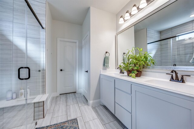 bathroom featuring a stall shower, a sink, baseboards, and double vanity