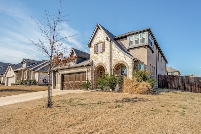 view of front of property featuring brick siding, concrete driveway, fence, stone siding, and a front lawn