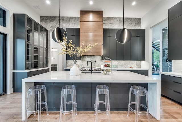 kitchen featuring a breakfast bar, pendant lighting, a large island, glass insert cabinets, and modern cabinets