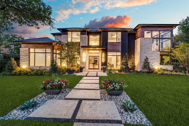 view of front of home with metal roof, stone siding, a front lawn, and a standing seam roof