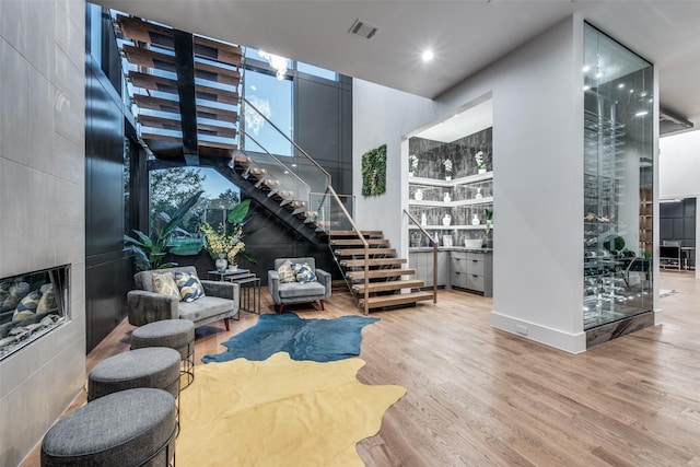 interior space featuring stairs, a tiled fireplace, wood finished floors, and visible vents