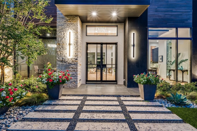 entrance to property with stone siding, french doors, and stucco siding