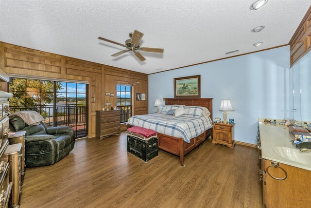 bedroom with a textured ceiling, dark wood finished floors, visible vents, and access to exterior