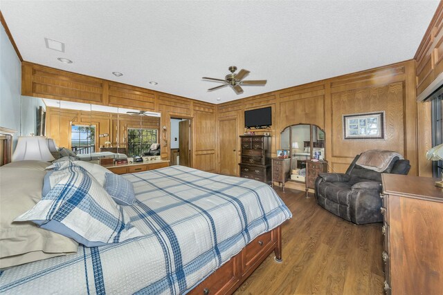 bedroom with a textured ceiling, wood walls, wood finished floors, and visible vents