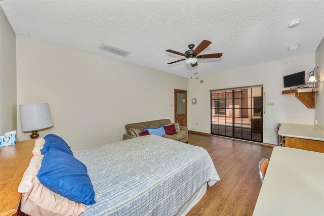 bedroom featuring a textured ceiling, wood finished floors, visible vents, and a ceiling fan