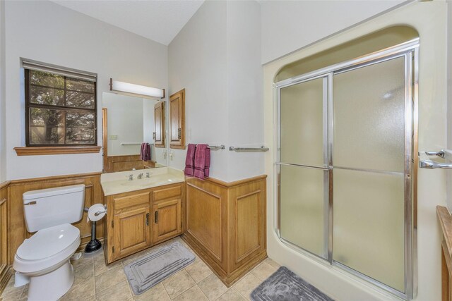 bathroom featuring a wainscoted wall, vanity, a shower stall, and toilet