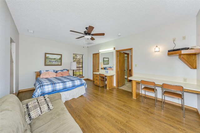 bedroom featuring light wood-style flooring, baseboards, ceiling fan, and a textured ceiling