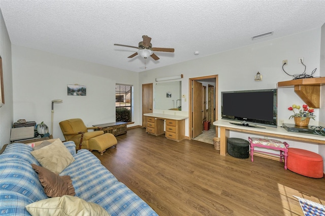 living area featuring dark wood-style floors, ceiling fan, visible vents, and a textured ceiling